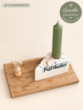 Pustekuchen-Kerzenhalter auf Holzsockel mit grüner Kerze und Trockenblumendeko